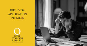 A man looking stressed and holding his head while reviewing paperwork and a laptop during the visa application process